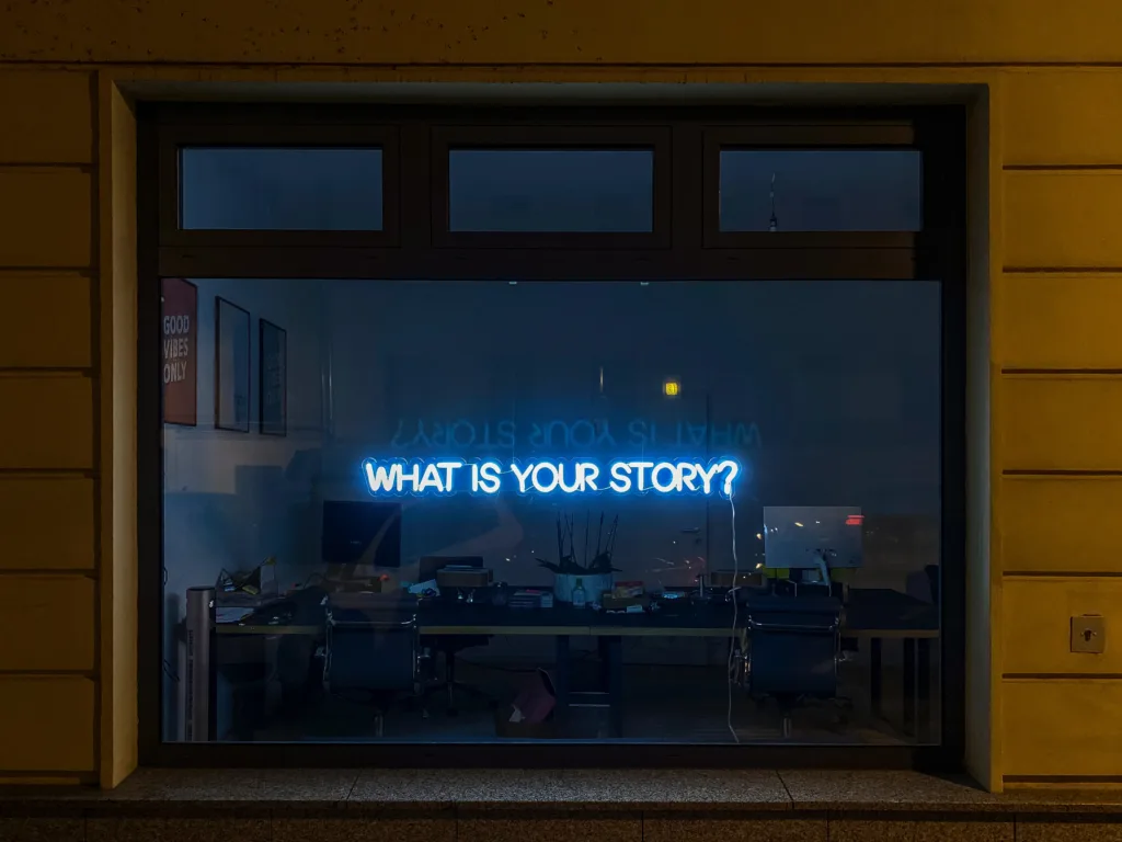 An office window with neon lights writing out "what is your story" to show off our creative content marketing service
