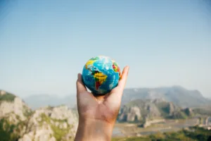 Hand holding a small globe with a mountain in the background to indicate multilingual SEO