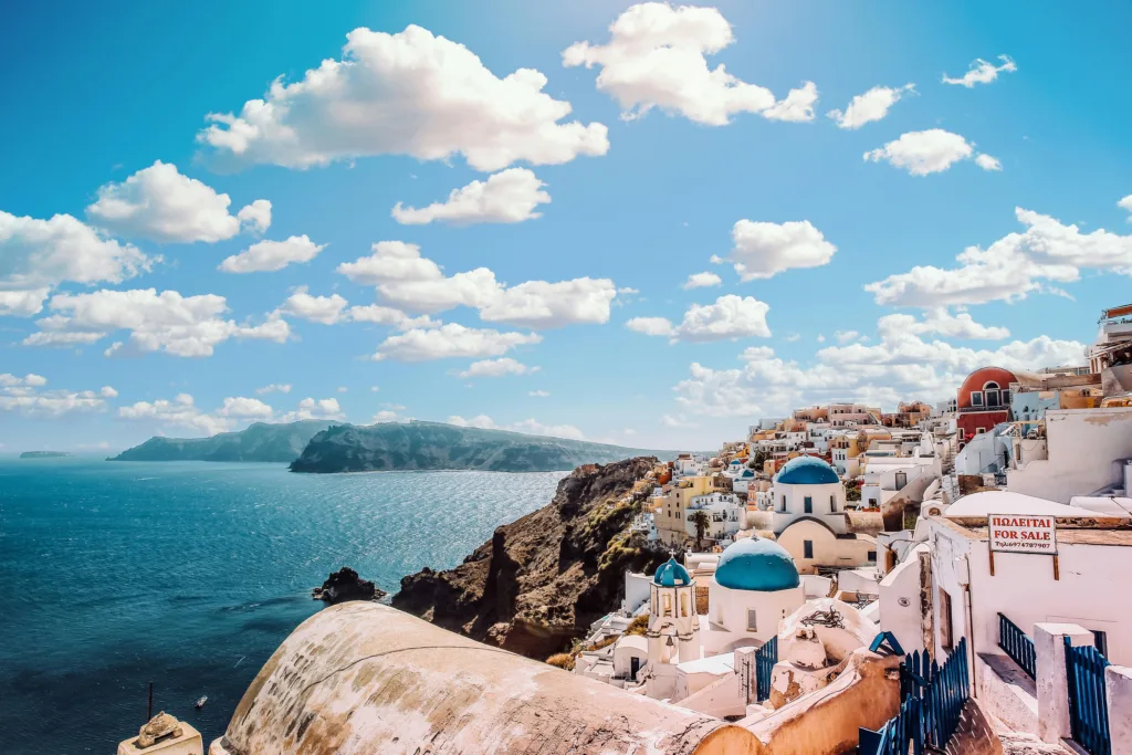 White Concrete House Near Body of Water Under White and Blue Cloudy Sky , Santorini, Greece