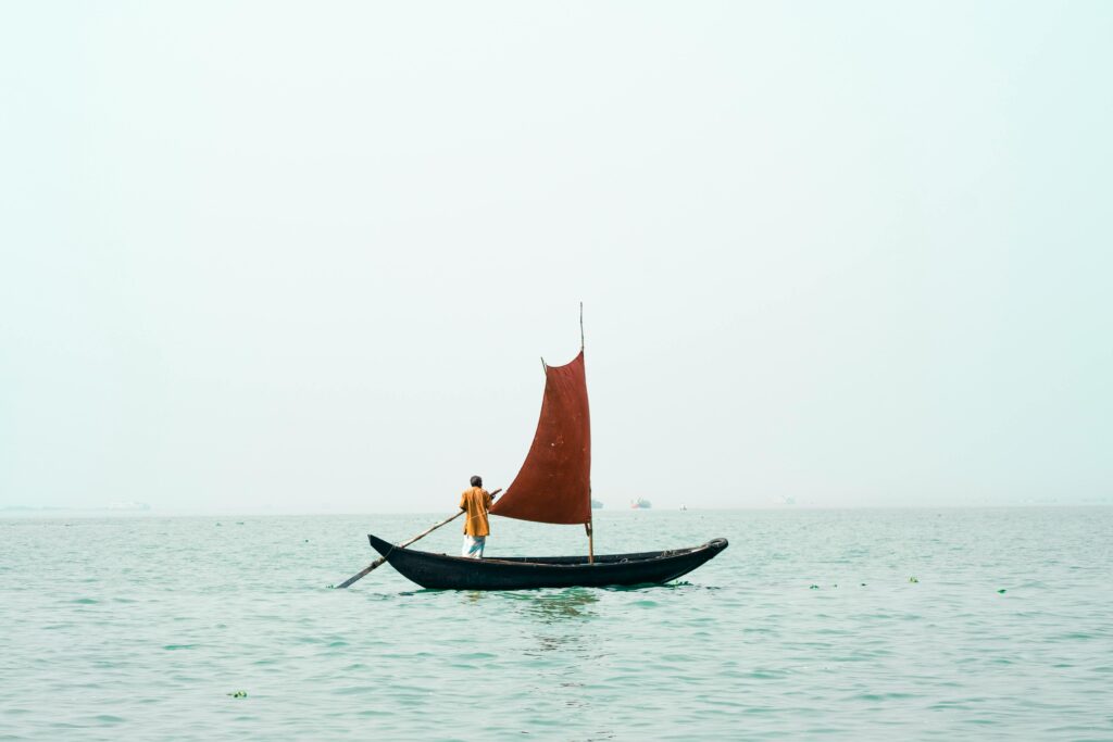 A Man Rowing A Small Boat With a Sail, Bangladesh. Asian Language Facts.