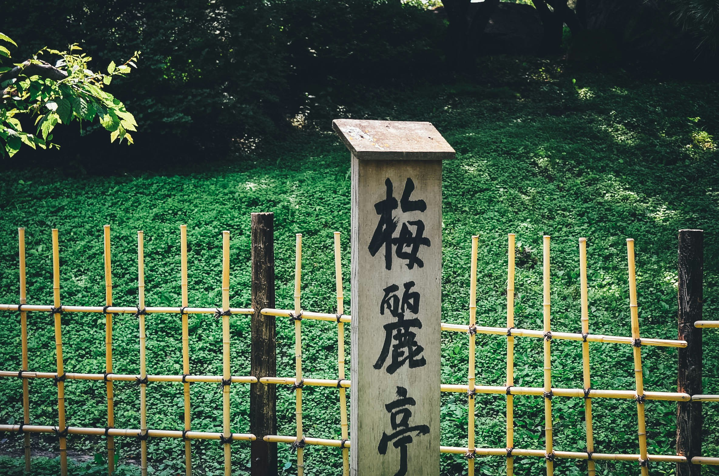 A fence post with Chinese characters against a green field backdrop, to symbolise brand language